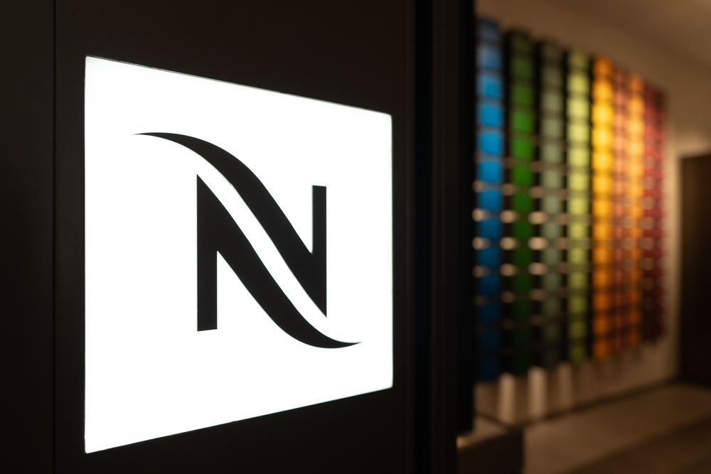 Ecran avec le logo Nespresso et des capsules en arrière-plan